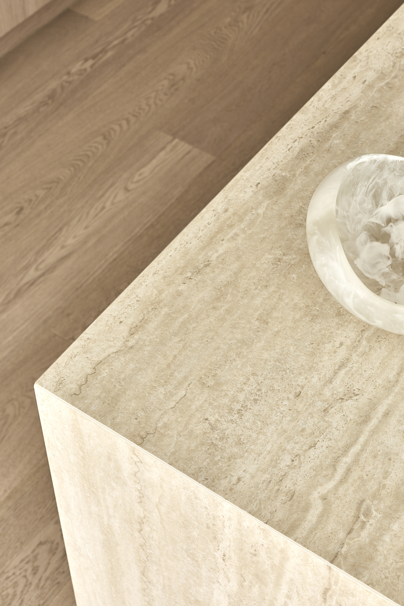 Beige marble countertop corner with a white bowl containing ice in the upper right corner.